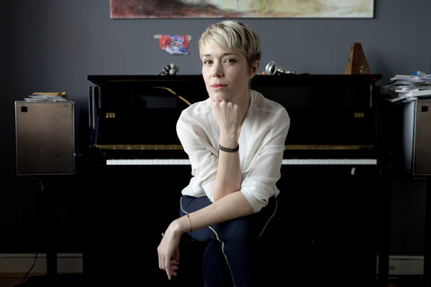 Portrait of blond woman sitting in her music room in front of piano stock photo