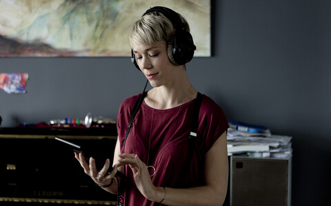Porträt einer blonden Frau, die mit Kopfhörern und digitalem Tablet Musik hört, lizenzfreies Stockfoto
