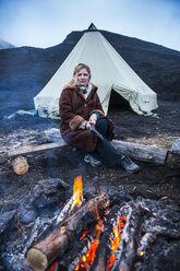 Frau in Pelzjacke vor einem Tipi-Zelt vor dem Vulkan Tolbachik, Kamtschatka, Russland - RUNF02027