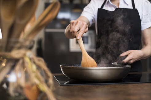 Nahaufnahme einer Frau beim Kochen in der Küche mit einer Pfanne - ABZF02370