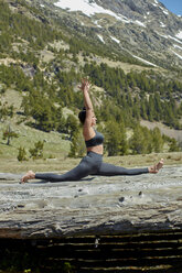 Junge Frau macht Yoga auf Baumstämmen in der Natur - JPF00389