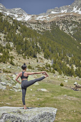 Young woman doing yoga in nature, standing on one leg, Hasta Padangustasana - JPF00398