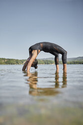 Junge Frau macht Yoga in der Natur, Rad-Pose am Seeufer - JPF00402