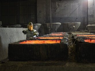 Industrie, Arbeiter prüft flüssiges Kupfer in Gussformen mit einer Zange - CVF01215