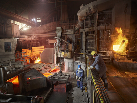 Industrie, Arbeiter hebt Kupferplatten mit Hallenkran zur Kühlung in Wasserbecken, lizenzfreies Stockfoto
