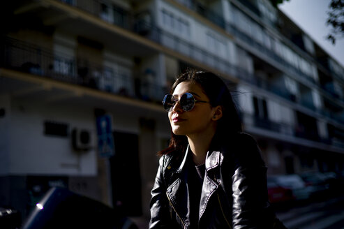 Portrait of young motorcyclist wearing sunglasses at evening twilight - OCMF00455