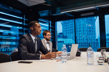 Businessmen listening during conference table meeting - CUF51308