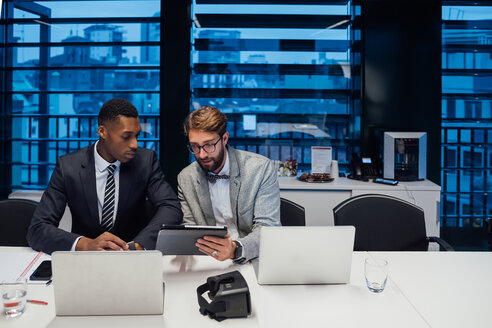 Businessmen looking at digital tablet during conference table meeting - CUF51311