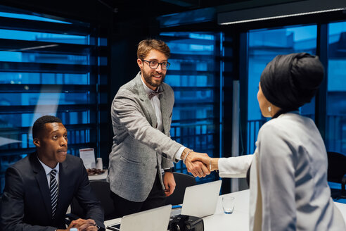 Businessman and female client shaking hands over conference table meeting - CUF51312