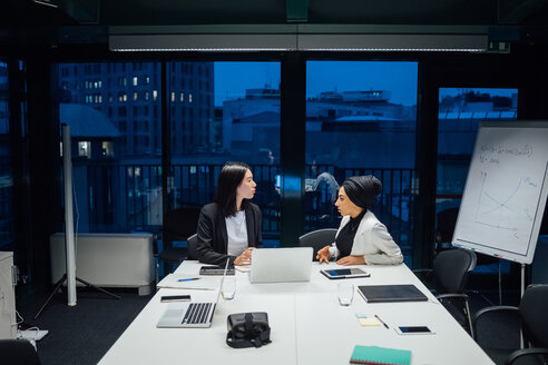 Businesswomen having discussion during conference table meeting - CUF51317