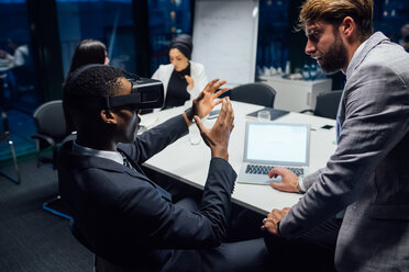 Businessman looking through virtual reality headset during conference table meeting - CUF51318