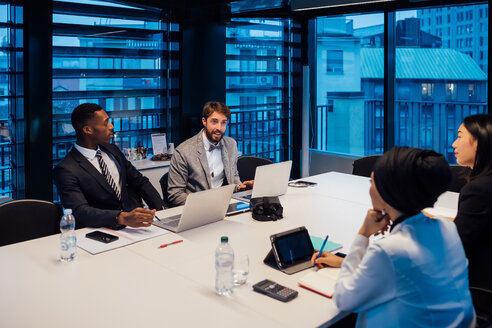 Businessmen and women having discussion during conference table meeting - CUF51350