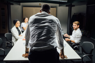 Geschäftsmann vor einem Team am Konferenztisch, Rückansicht - CUF51351