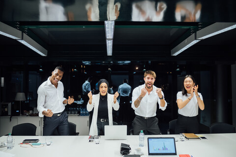 Selbstbewusstes Geschäftsteam beim Feiern am Konferenztisch, Porträt, lizenzfreies Stockfoto