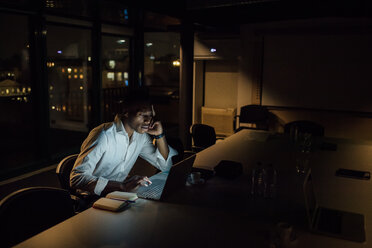 Tired young businessman in office at night typing on laptop - CUF51368
