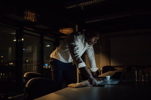 Junger Geschäftsmann im Büro bei Nacht mit Blick auf den Laptop - CUF51370