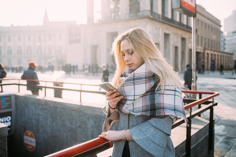 Junge Frau schaut in der U-Bahn-Station auf ihr Smartphone, Mailand, Italien, lizenzfreies Stockfoto