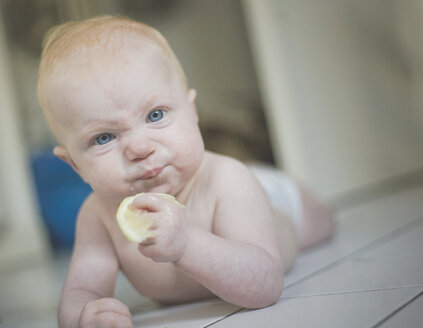 Portrait of baby girl eating a lemon - IHF00007