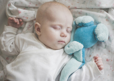 Seeping baby girl with a blue toy stock photo