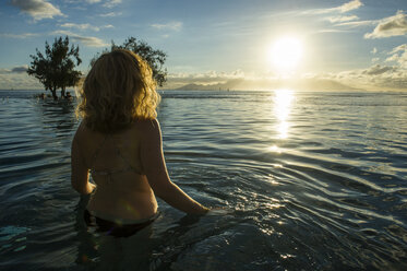 French Polynesia, Tahiti, Papeete, woman enjoying the sunset in an infinity pool - RUNF02061