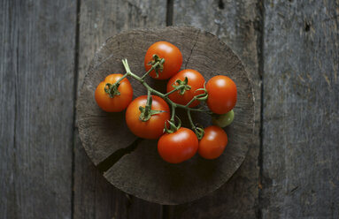 Tomatoes on vine on wooden tree slice - BLEF03246