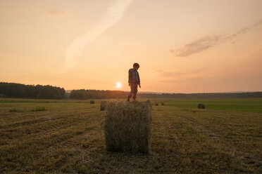 Marienjunge steht auf einem Heuballen auf einem Feld, Ural, Russland - BLEF03253