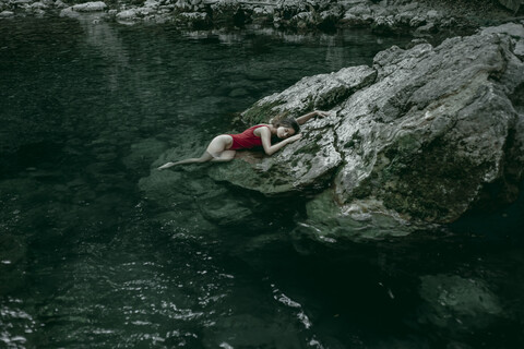 Kaukasische Frau liegt auf Felsen in einem Wasserbecken, lizenzfreies Stockfoto