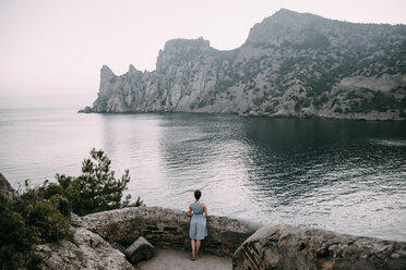 Caucasian woman standing at stone wall admiring ocean - BLEF03260