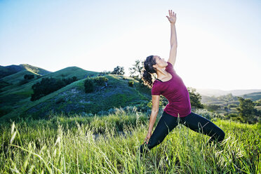 Mixed Race woman practicing yoga on hill - BLEF03310