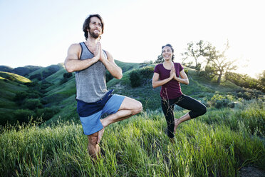 Lächelndes Paar übt Yoga auf einem Hügel - BLEF03312