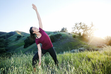 Gemischtrassige Frau übt Yoga auf einem Hügel - BLEF03315