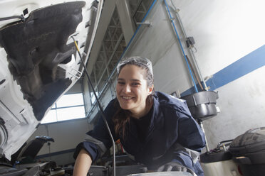 Lächelnder hispanischer Mechaniker, der einen Automotor repariert - BLEF03347