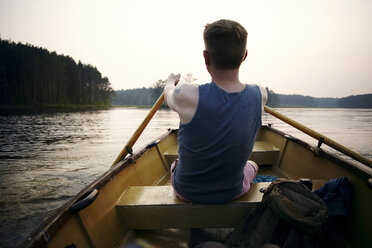 Caucasian man paddling in rowboat at sunset - BLEF03360