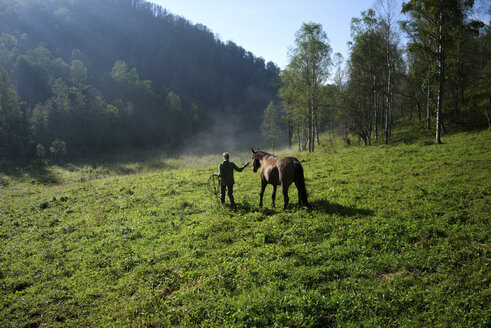 Kaukasisches Mädchen geht mit Pferd im Feld spazieren - BLEF03371