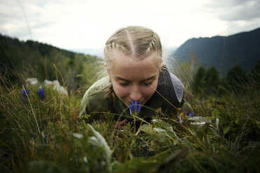 Caucasian girl smelling wildflower laying in grass on hill - BLEF03376