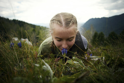 Kaukasisches Mädchen riecht an Wildblumen und liegt im Gras auf einem Hügel - BLEF03376