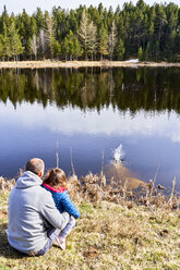 Frankreich, Pyrenäen, Rückenansicht von Vater und kleiner Tochter, die vor einem See sitzen und die Aussicht genießen - GEMF02960