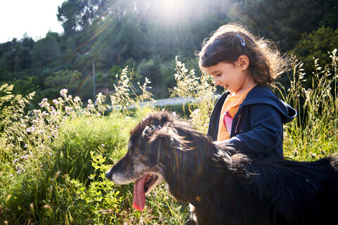 Happy toddler girl walking with dog in nature stock photo