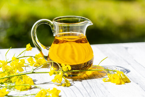 Rapeseed oil in jar with rape blossom on wood - SARF04268