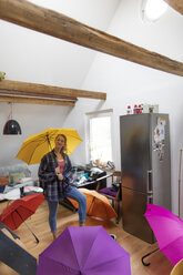 Junge Frau mit Regenschirmen zu Hause - GUSF01988