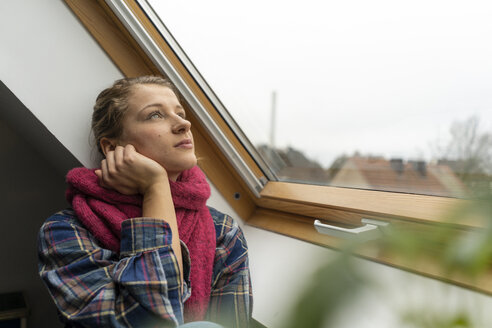 Nachdenkliche junge Frau schaut aus dem Fenster - GUSF02019
