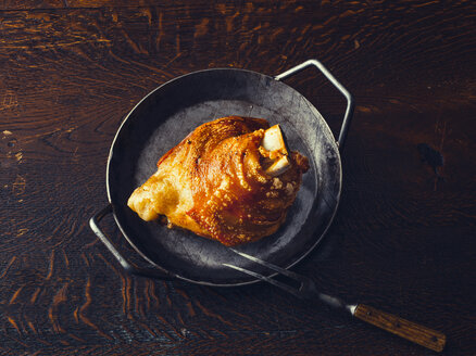 Crispy roasted pork knuckle in a pan on wooden table - PPXF00195