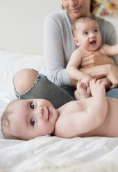 Caucasian mother with twin baby daughters on bed - BLEF03412