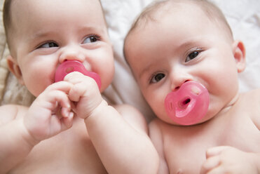 Caucasian twin baby girls sucking pacifiers - BLEF03416