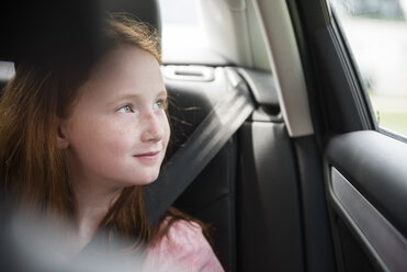 Lächelndes kaukasisches Mädchen im Auto, das aus dem Fenster schaut - BLEF03440
