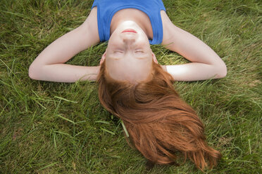 Caucasian girl laying in grass with hands behind head - BLEF03442