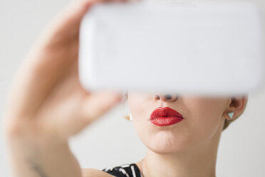 Red lips of woman posing for cell phone selfie - BLEF03458