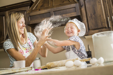 Kaukasische Mutter und Tochter, die mit Mehl um Essen kämpfen - BLEF03469