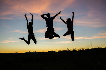 Silhouette of friends jumping for joy at sunset - BLEF03475