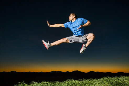 Caucasian man jumping at sunset - BLEF03477